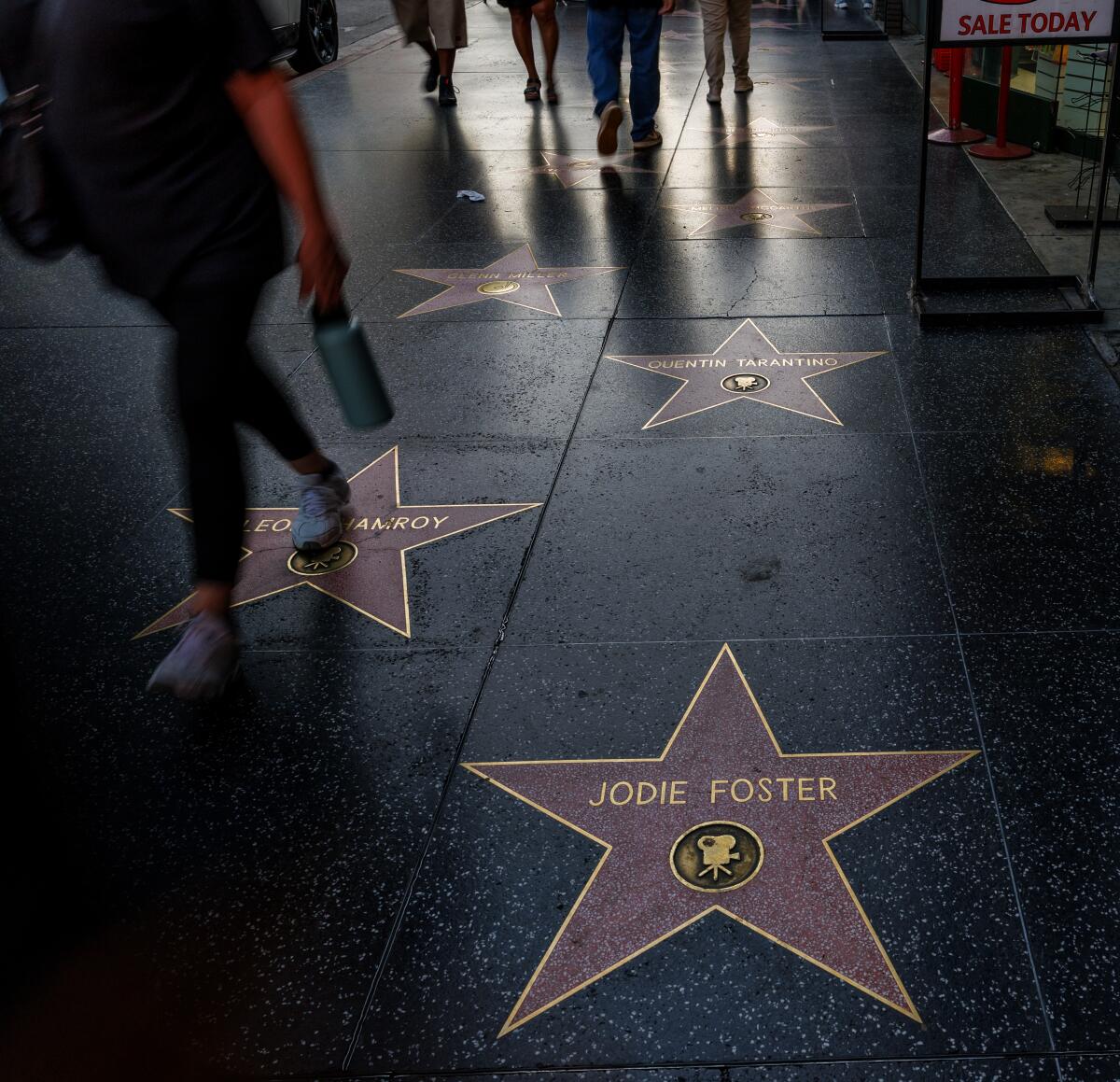 Los turistas caminan por las estrellas de celebridades en Hollywood Boulevard frente al Teatro Dolby.