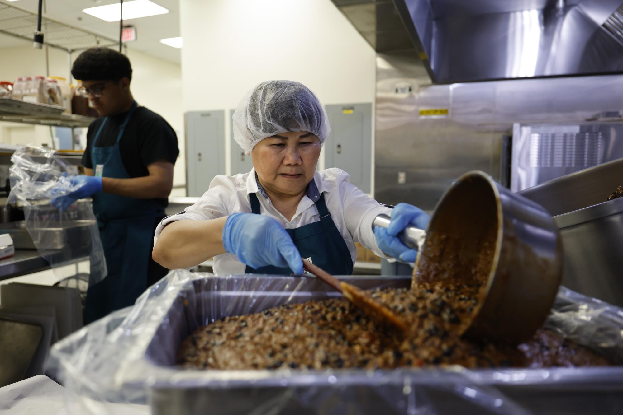 Carol Chan sirve chili de carne y frijoles en la cocina de producción central del Distrito Unificado de Alhambra.