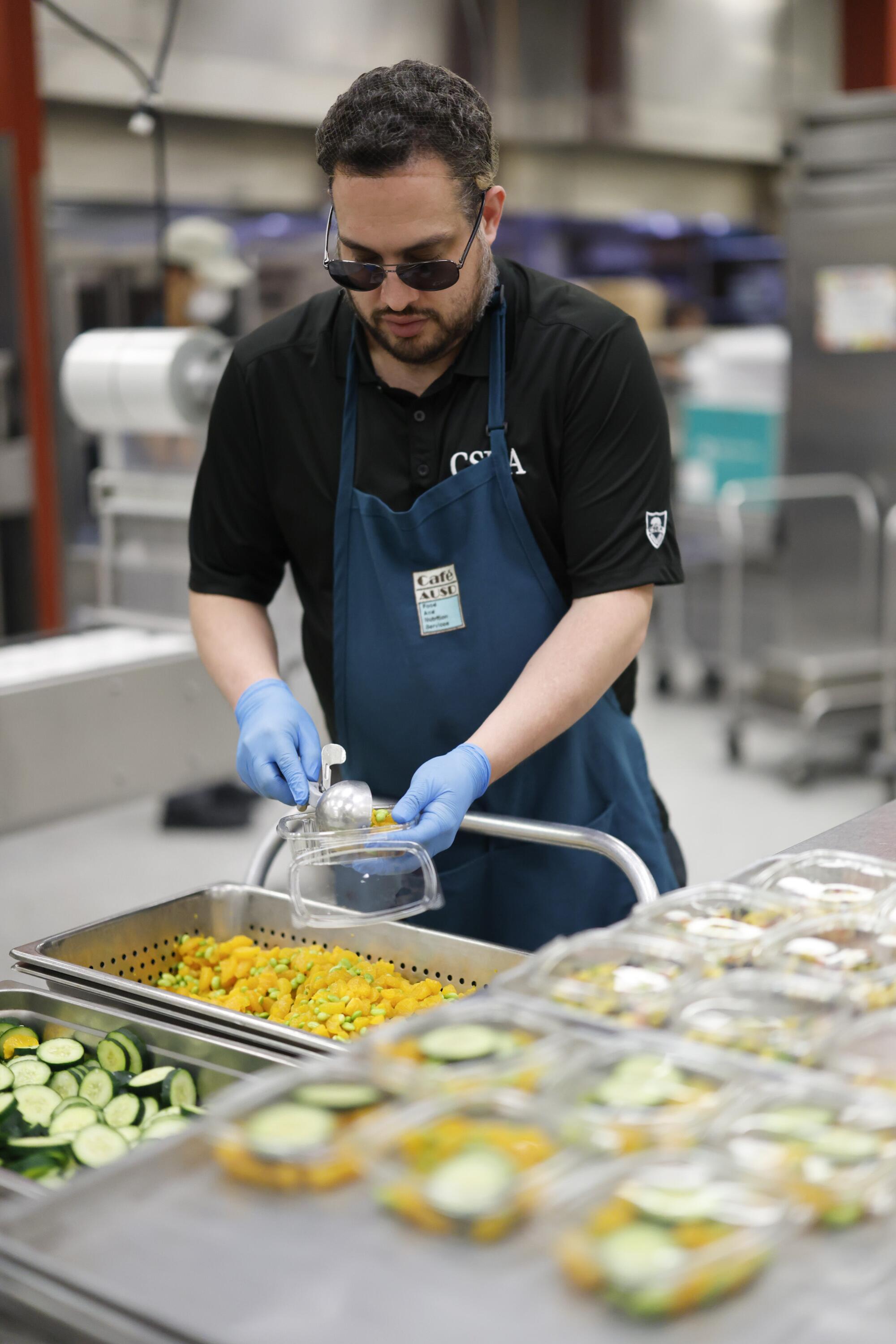 Andrew Vasquez prepara salsa de maíz y frijoles negros en la cocina de producción central del Distrito Escolar Unificado de Alhambra.