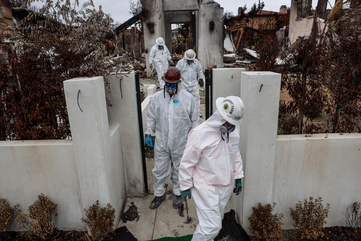 Equipos de la EPA peinan las ruinas en busca de materiales peligrosos en una casa