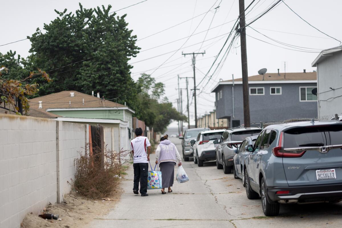 Dos personas abandonan un sitio de distribución de alimentos el sábado en Long Beach.