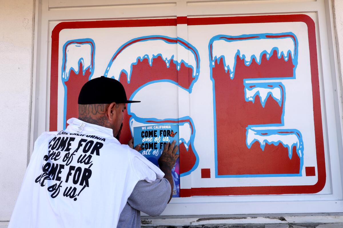 un hombre coloca un cartel en parte de un "Sin hielo" mural