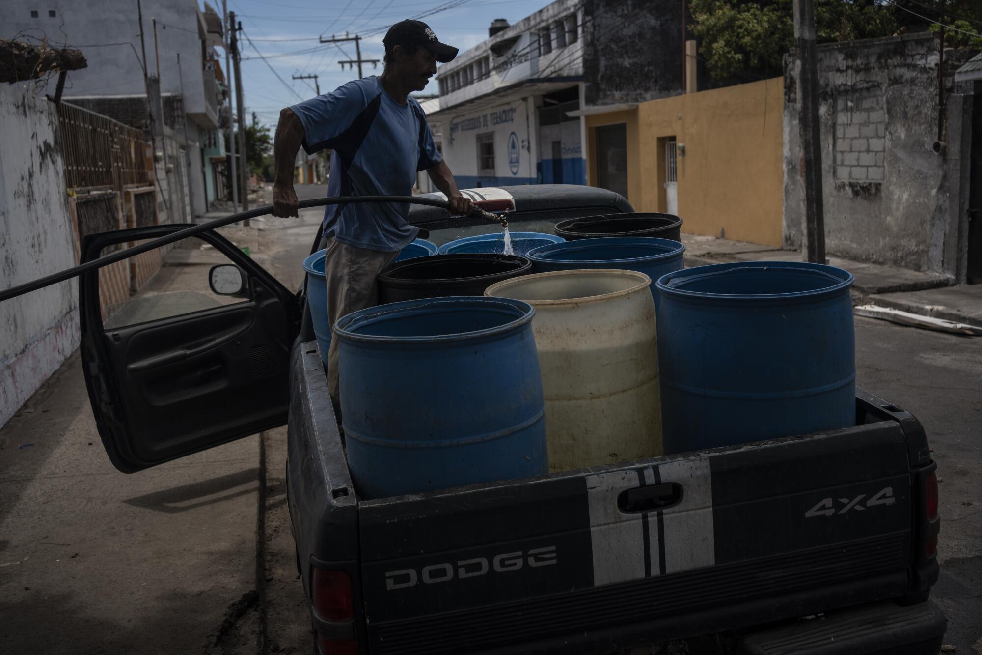 Un hombre llena contenedores con agua debido a la escasez provocada por las altas temperaturas.