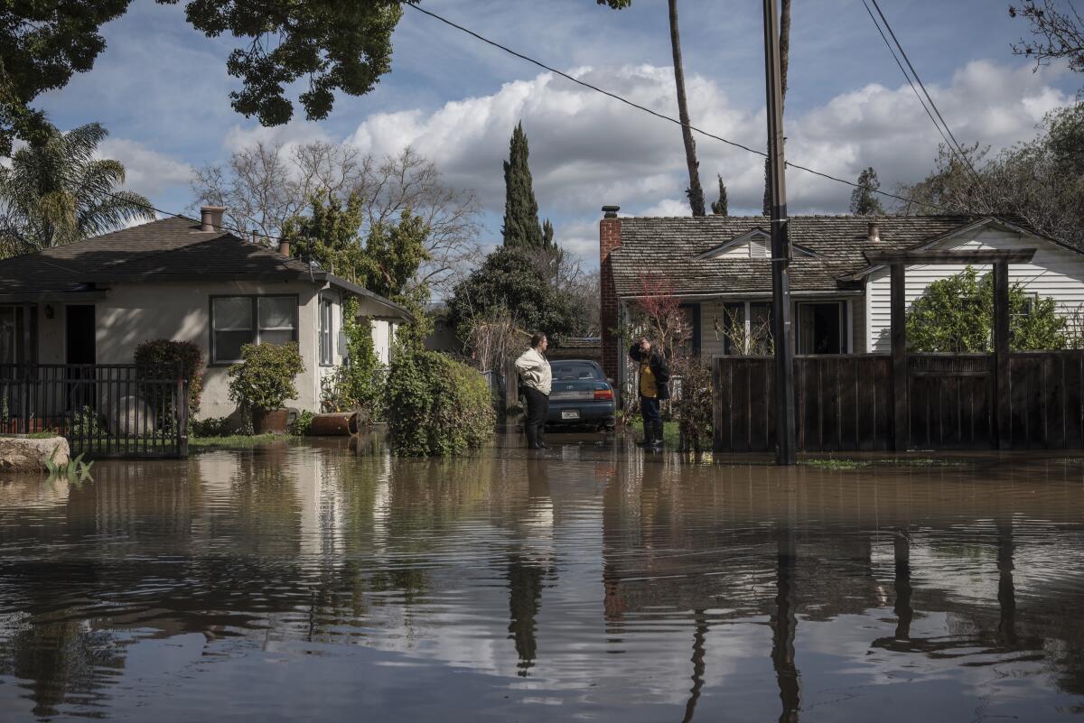 Los vecinos conversan en medio de las inundaciones en un barrio residencial. 