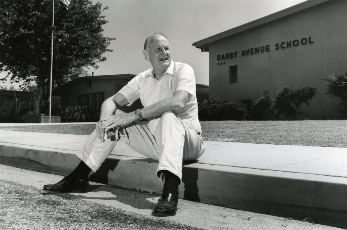 Robert Docter está sentado en la acera frente a una escuela en Northridge. 