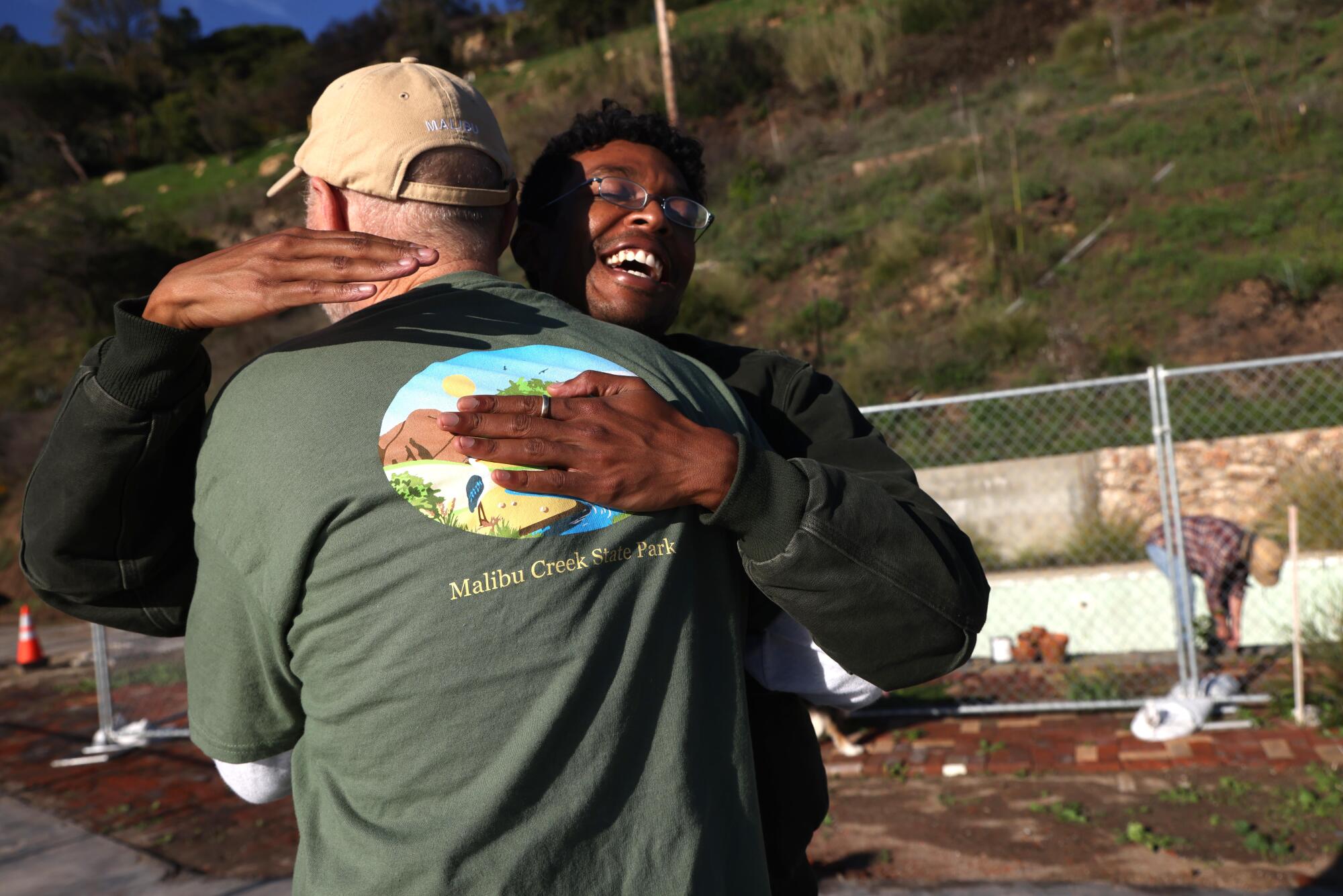 El artista Evan Hall, a la derecha, saluda a Kraig Hill, en la propiedad de Hill donde su casa fue destruida en el incendio de Palisades en Malibú.